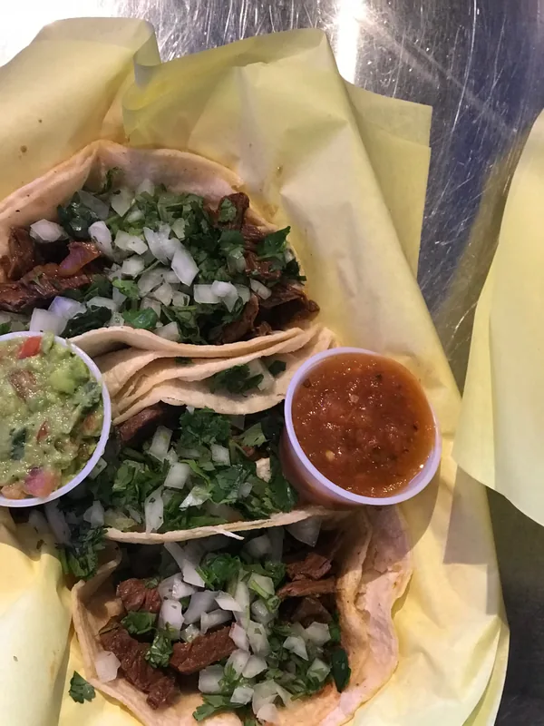 Carnitas street tacos with cilantro, onion, guacamole and salsa